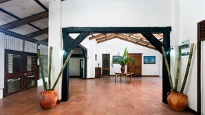 A spacious hallway with terracotta tiled flooring, wooden beams, and potted plants. - Stonefield Estate Villa Resort (Soufrière)