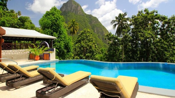 A poolside area with lounge chairs, a covered seating area, and a mountain backdrop. - Stonefield Estate Villa Resort (Soufrière)