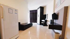 Een moderne hotelkamer met een koelkast, een flatscreen televisie, een bureau en een zithoek met een bank.