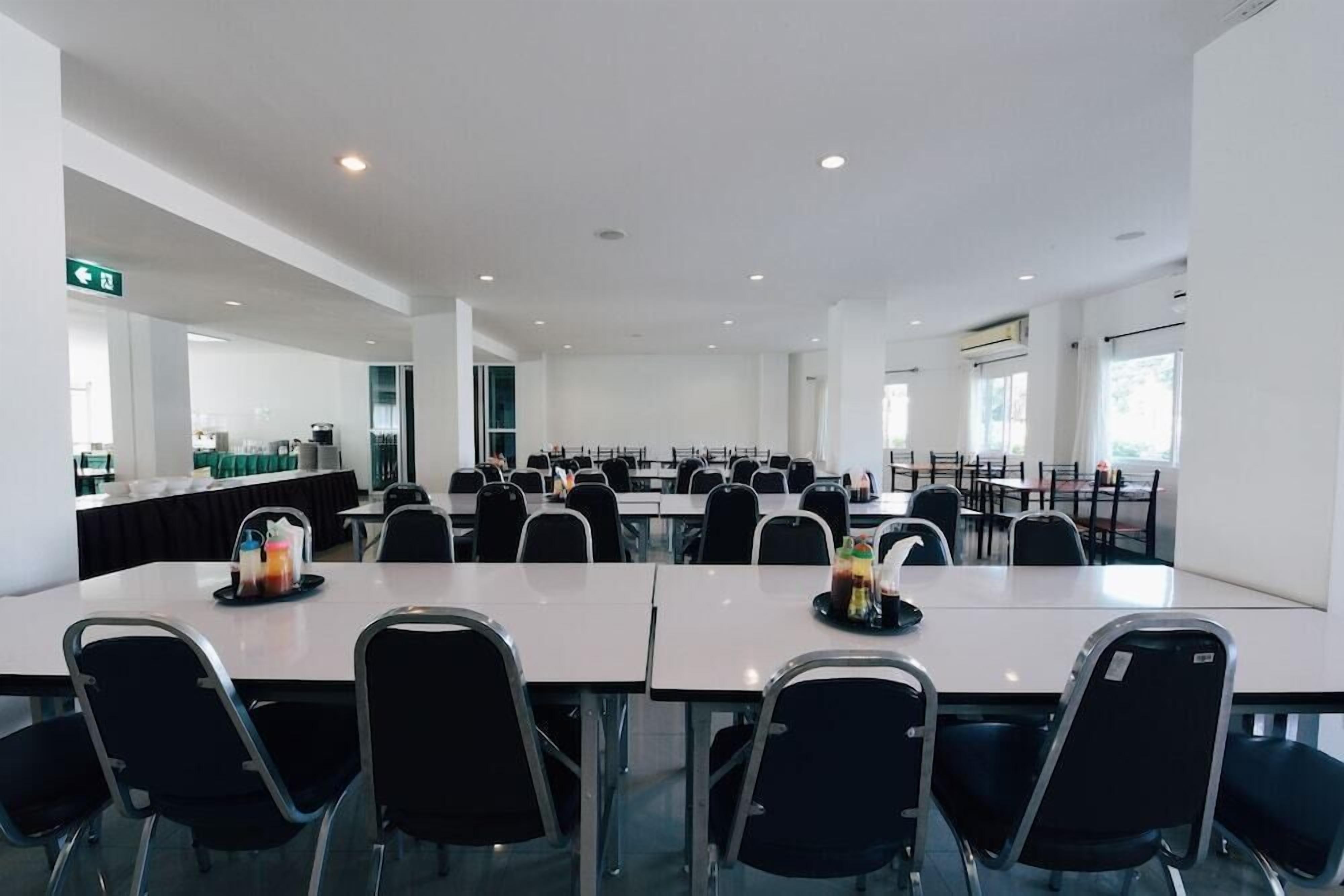 A spacious conference room with multiple tables and chairs, large windows, and a clean, modern design.