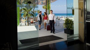 A modern hotel lobby with a view of a beach and palm trees. - Brisa (Benidorm)