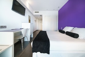 Une chambre d’hôtel moderne équipée d’un lit, d’un bureau, d’une chaise et d’un téléviseur.