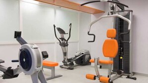 Un gimnasio con diversos equipos de ejercicio, como una máquina de remo, una elíptica y un banco de pesas.