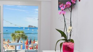 A room with a view of a beach, a white desk, a pink orchid, and a TV mounted on the wall. - Brisa (Benidorm)