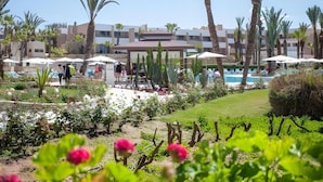 Un resort con piscina, palmeras y un jardín con flores rosadas.