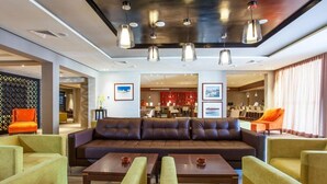 A modern lobby with a leather sofa, yellow armchairs, and a bar area in the background. - Dunes d Or Ocean Club Agadir (Agadir)