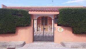 Edifici amb teulada d'atlesos, entrada tancada per una reixa i un senyal que indica un negoci o establiment.
