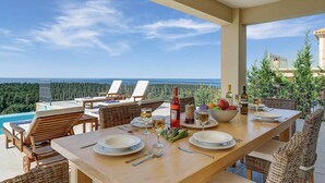 A dining area with a view of the ocean, a pool, and outdoor seating. - Villa Persephone (Kefalonia)