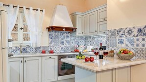 A kitchen with white cabinets, a built-in oven, and a tiled backsplash. - Villa Persephone (Kefalonia)