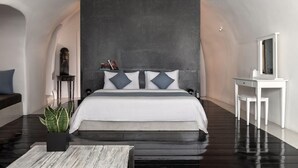 A modern bedroom with a large bed, a small side table, a mirror, and a potted plant. - Alta Mare By Andronis (Santorini)