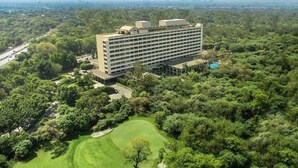 A large hotel with multiple floors, surrounded by lush greenery and a golf course.