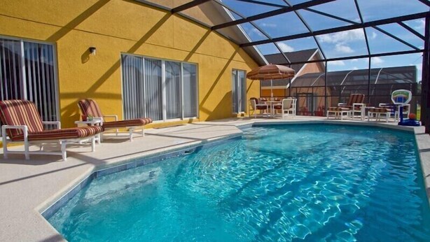 Une piscine intérieure à l’eau d’un bleu cristallin, entourée de chaises longues et d’un espace de détente abrité.