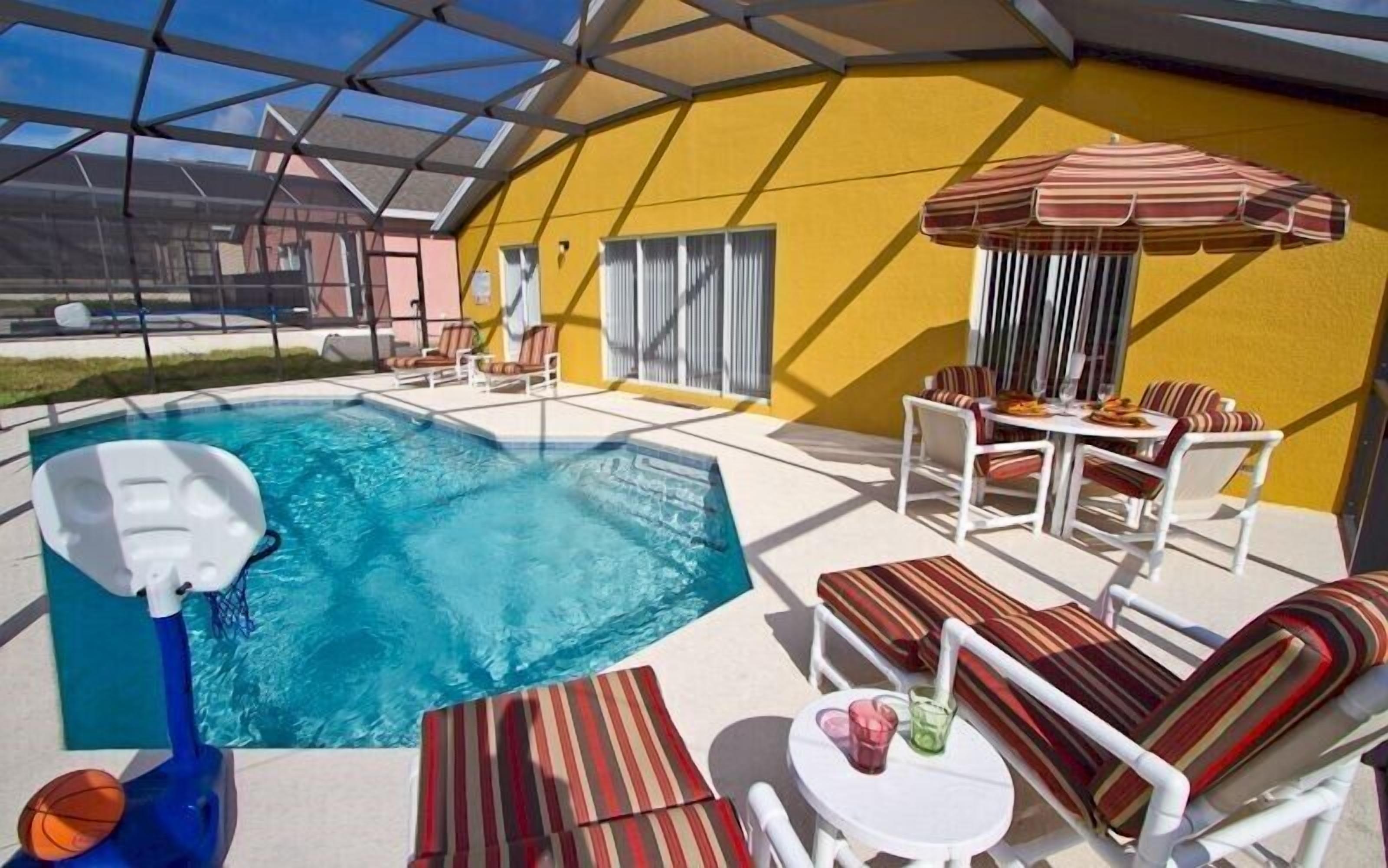 Ett poolområde med ett bubbelbad, solstolar och ett matbord med stolar.