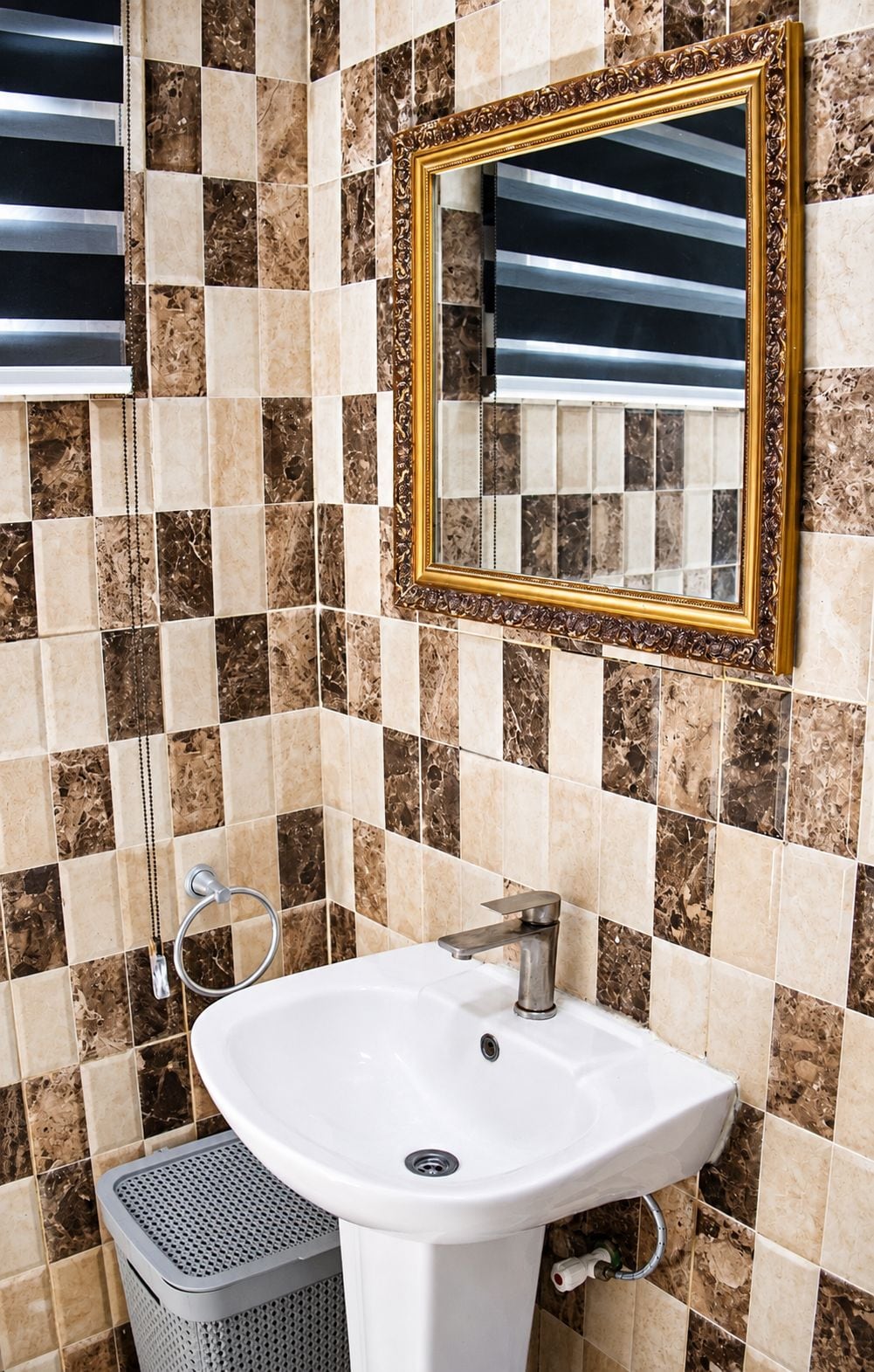 A bathroom with a white sink, a gold-framed mirror, and a towel rack.