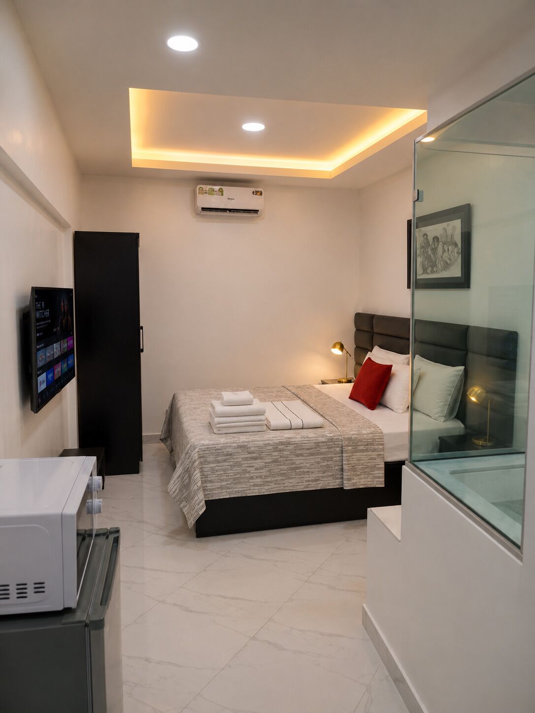 A modern bedroom with a bed, bedside table, lamp, and a television mounted on the wall.
