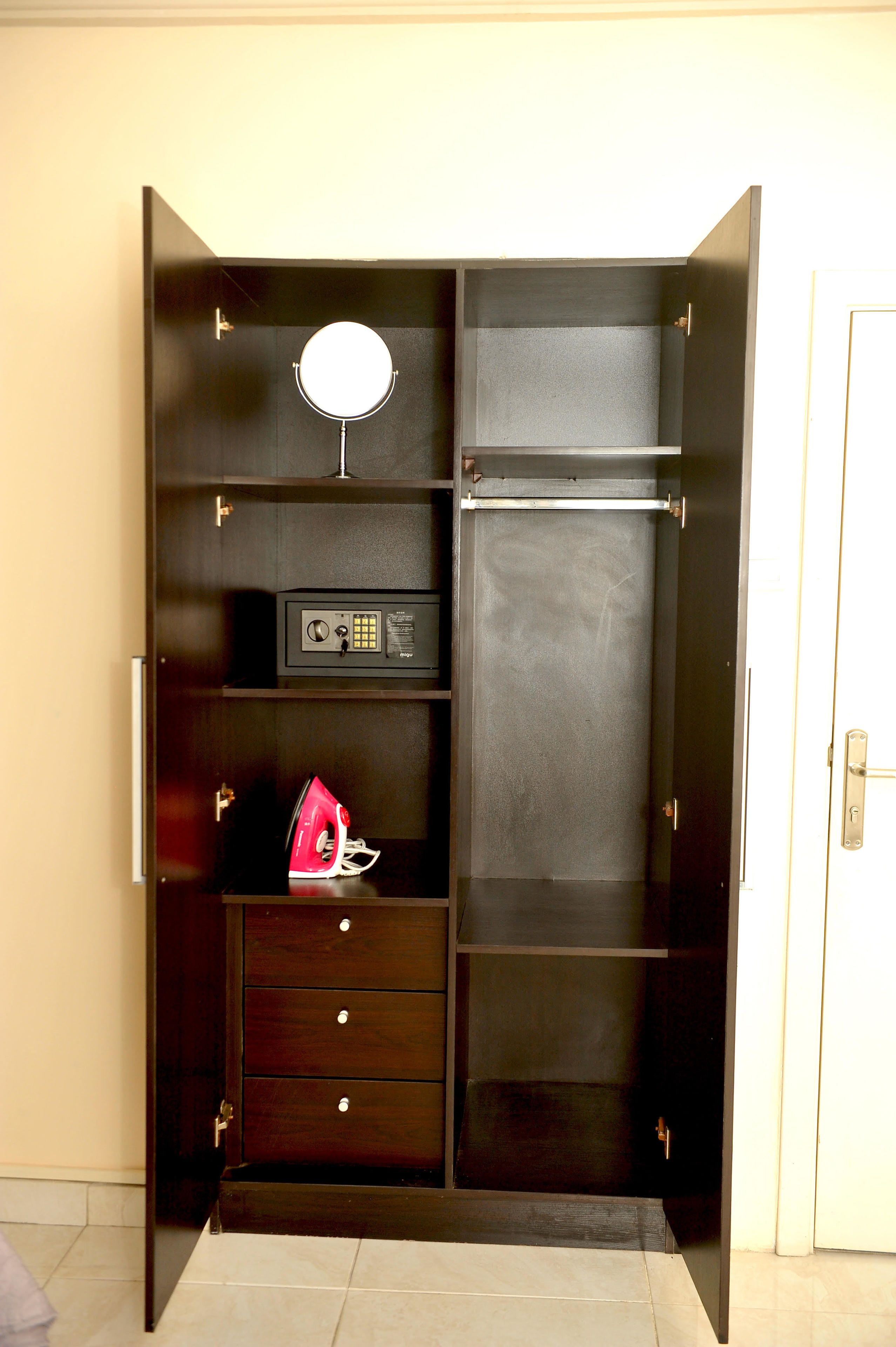 A dark wooden wardrobe with a mirror, a radio, and a red handbag.