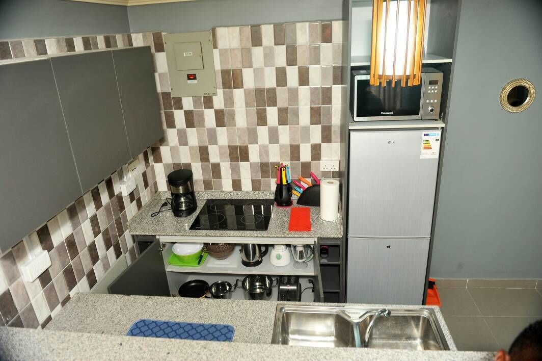A compact kitchen with a microwave, stove, and various utensils.