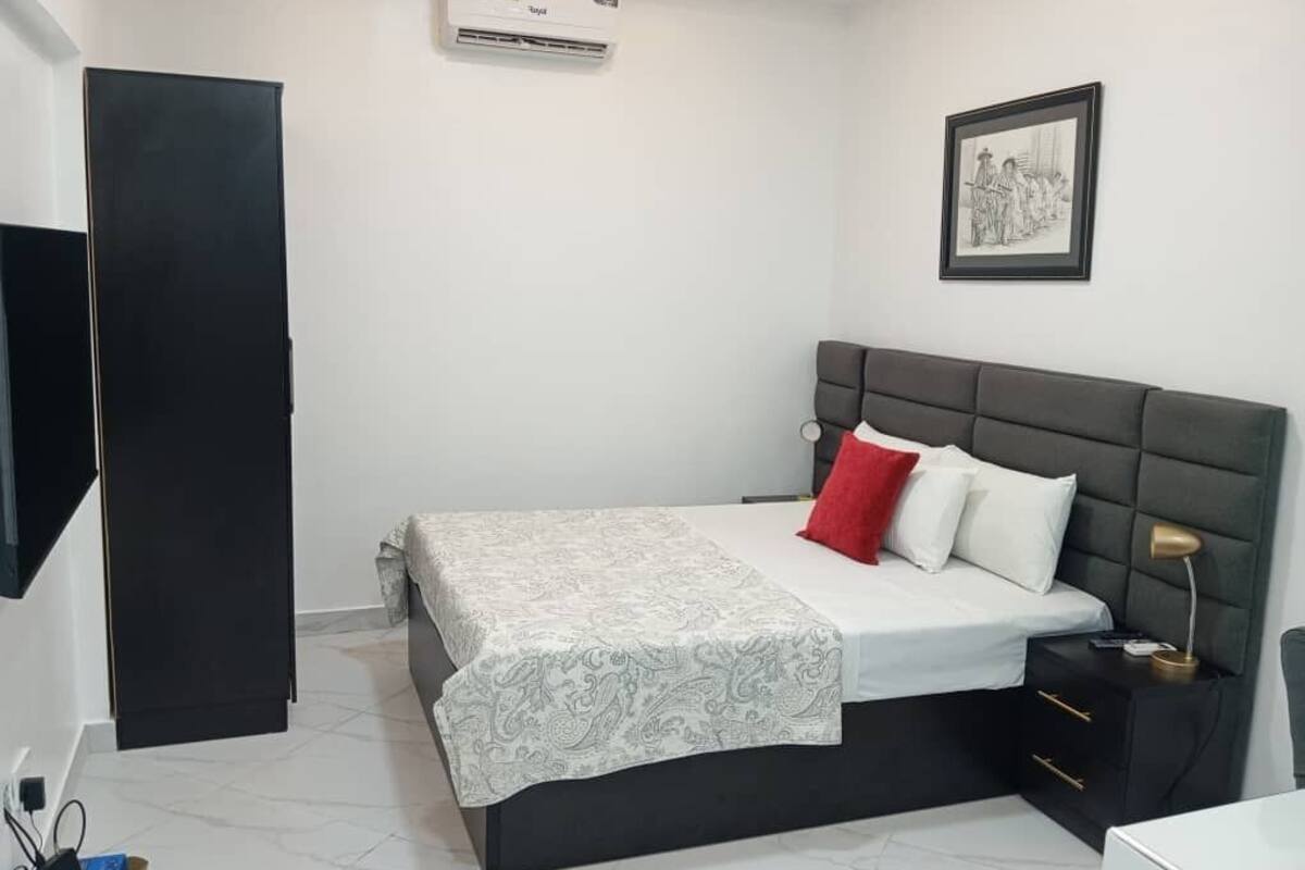 Un dormitorio con cama, mesita de noche y aire acondicionado instalado en la pared.