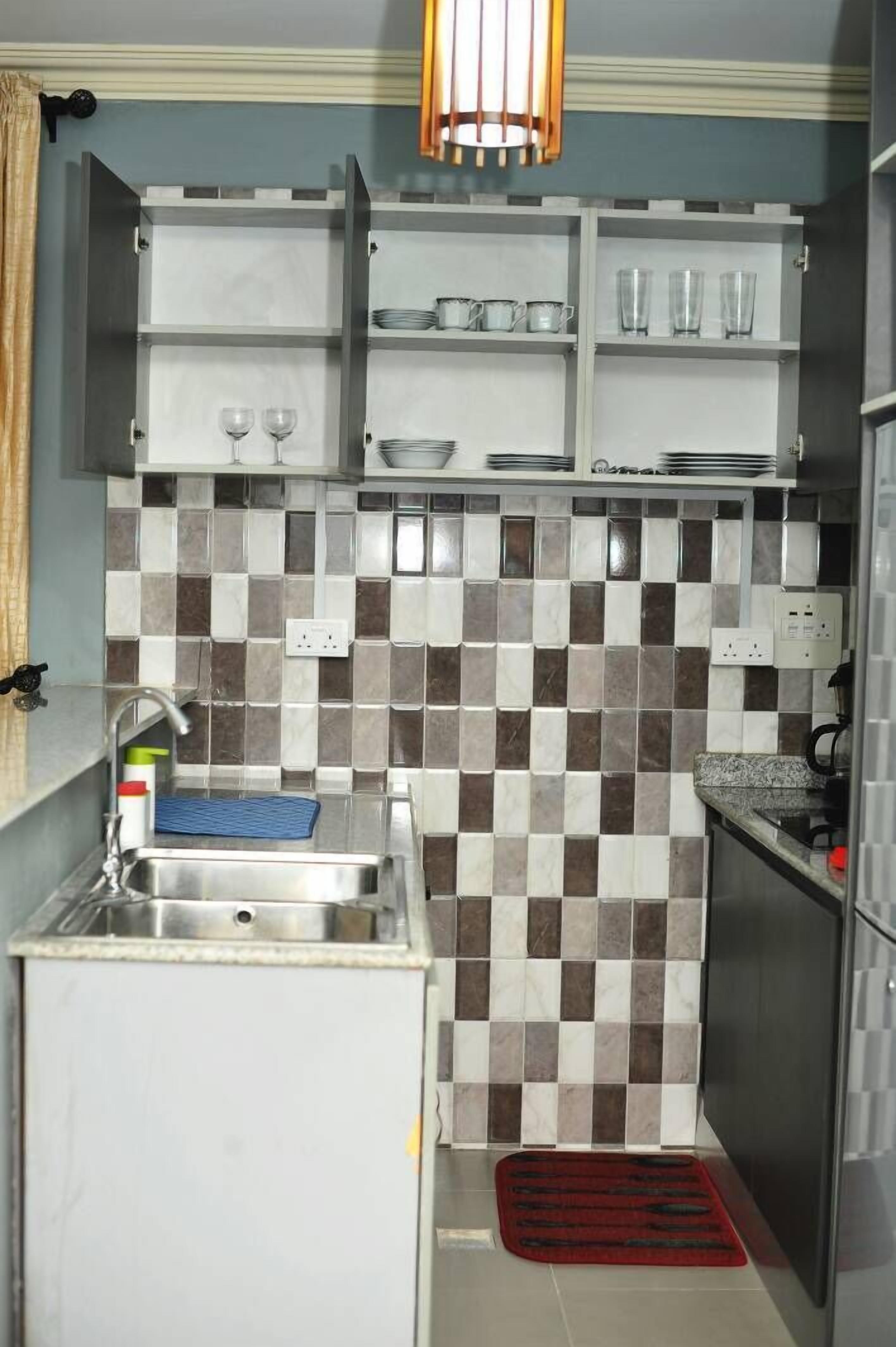 A compact kitchen with a tiled backsplash, a built-in sink, and upper cabinets.