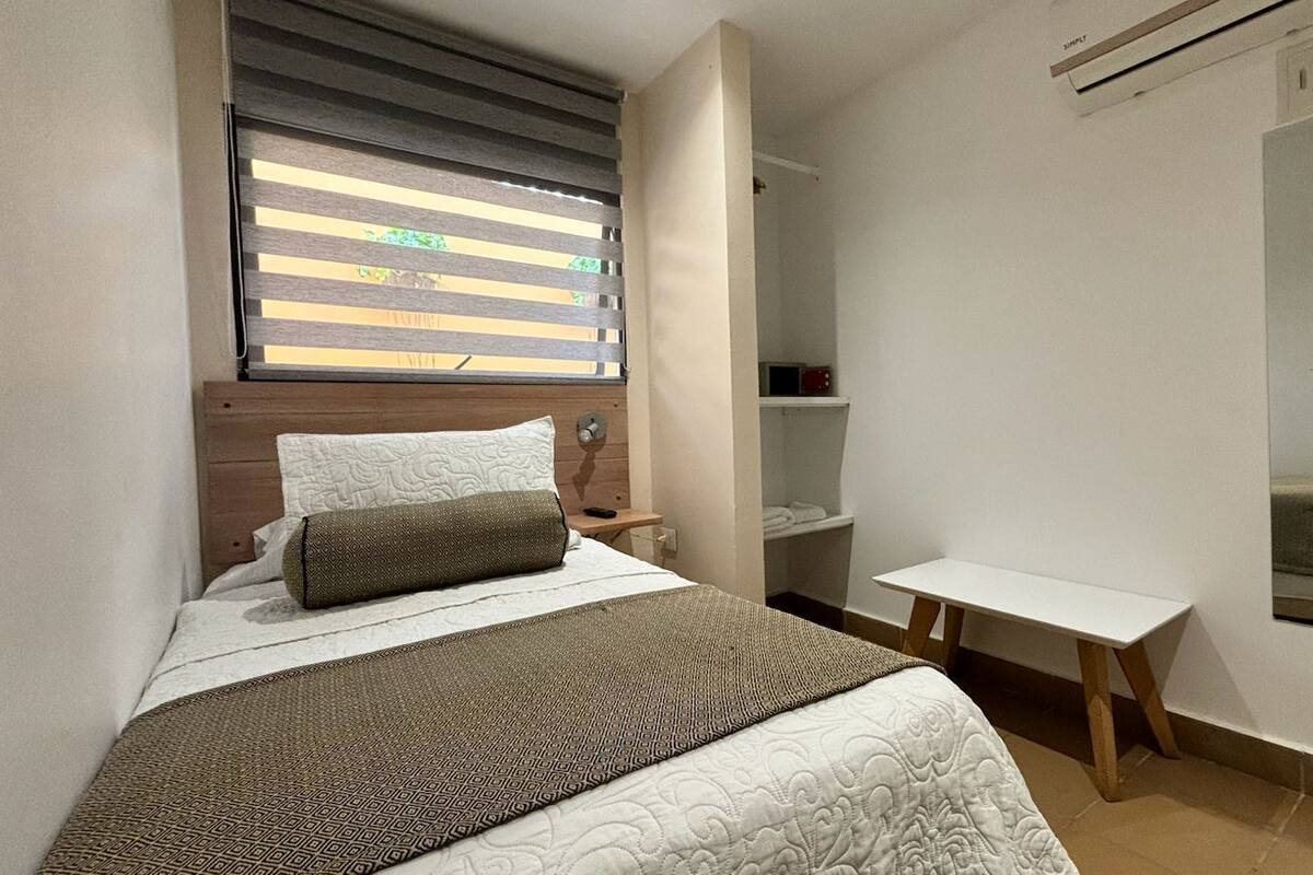 A bedroom with a bed, bedside table, and a mirror on the wall.