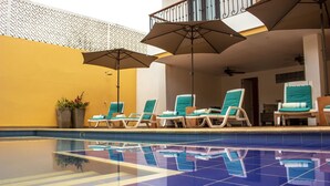 Une piscine avec des chaises longues et des parasols.
