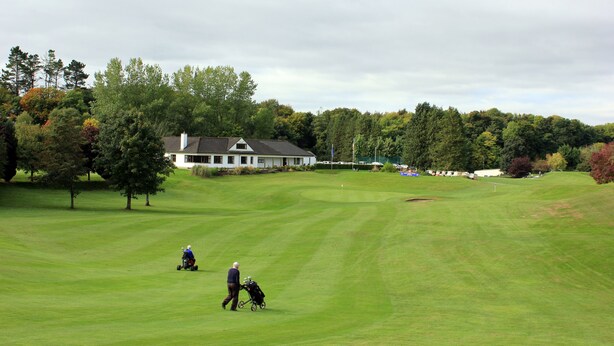 Un terrain de golf avec un club-house en arrière-plan.