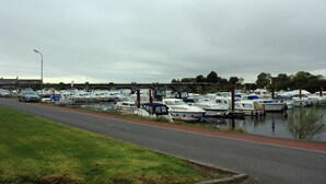 Un port de plaisance où des bateaux sont amarrés le long d’une promenade dallée.
