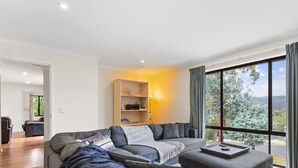 A modern living room with a grey sectional sofa, a small table, and a bookshelf.