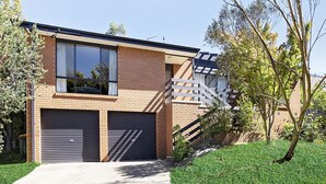 A modern two-story house with a brick facade, large windows, and a covered driveway.