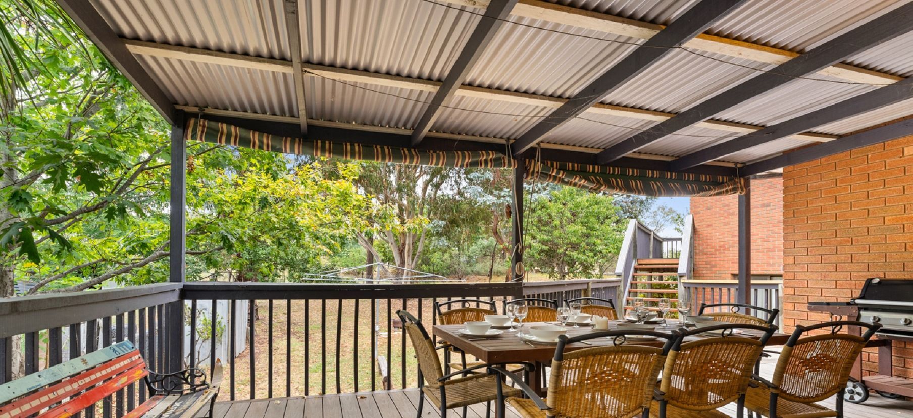 An outdoor patio with a covered seating area, a brick wall, and a grill.