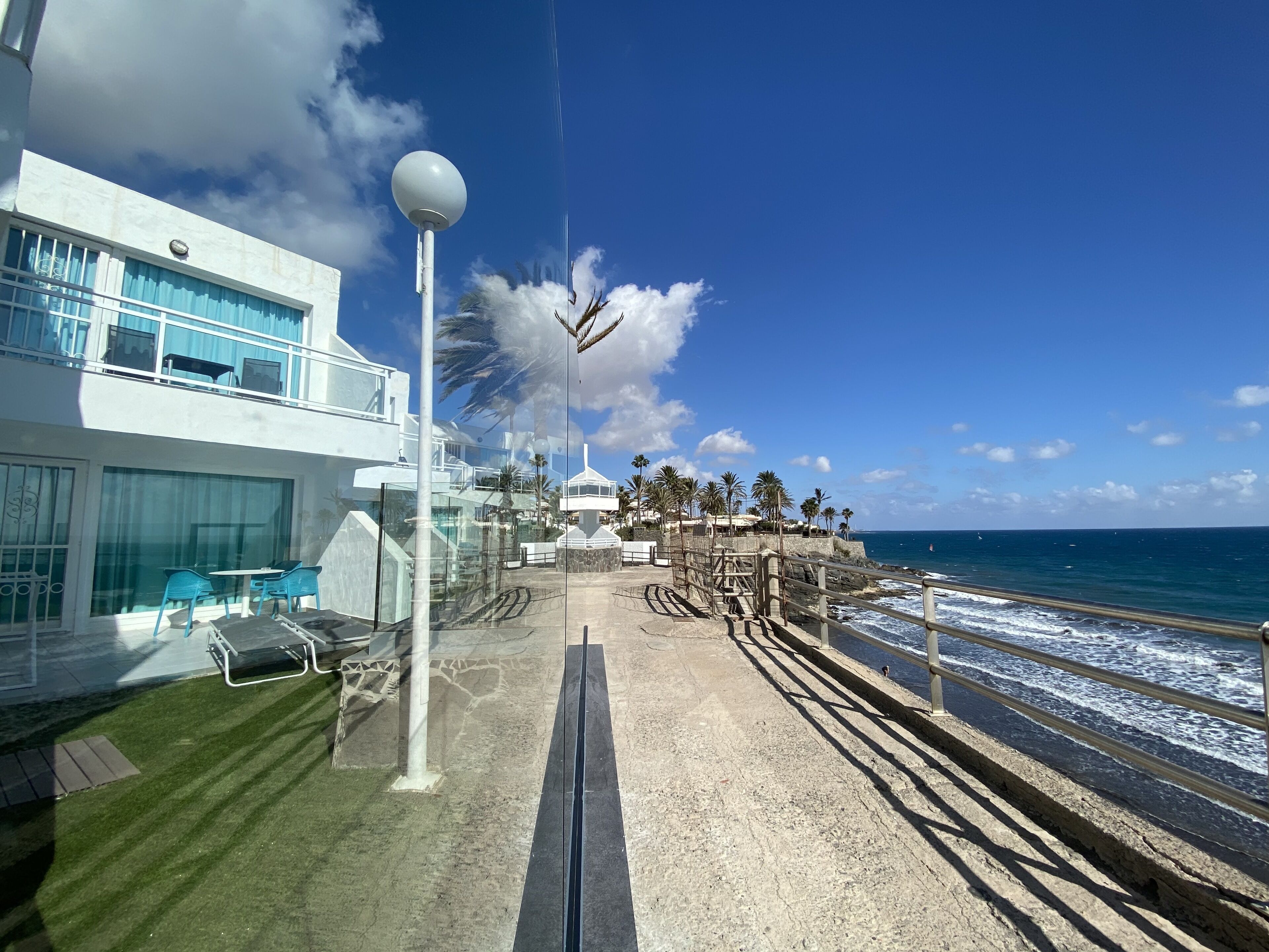 A coastal hotel with a balcony, outdoor seating, and a view of the ocean.