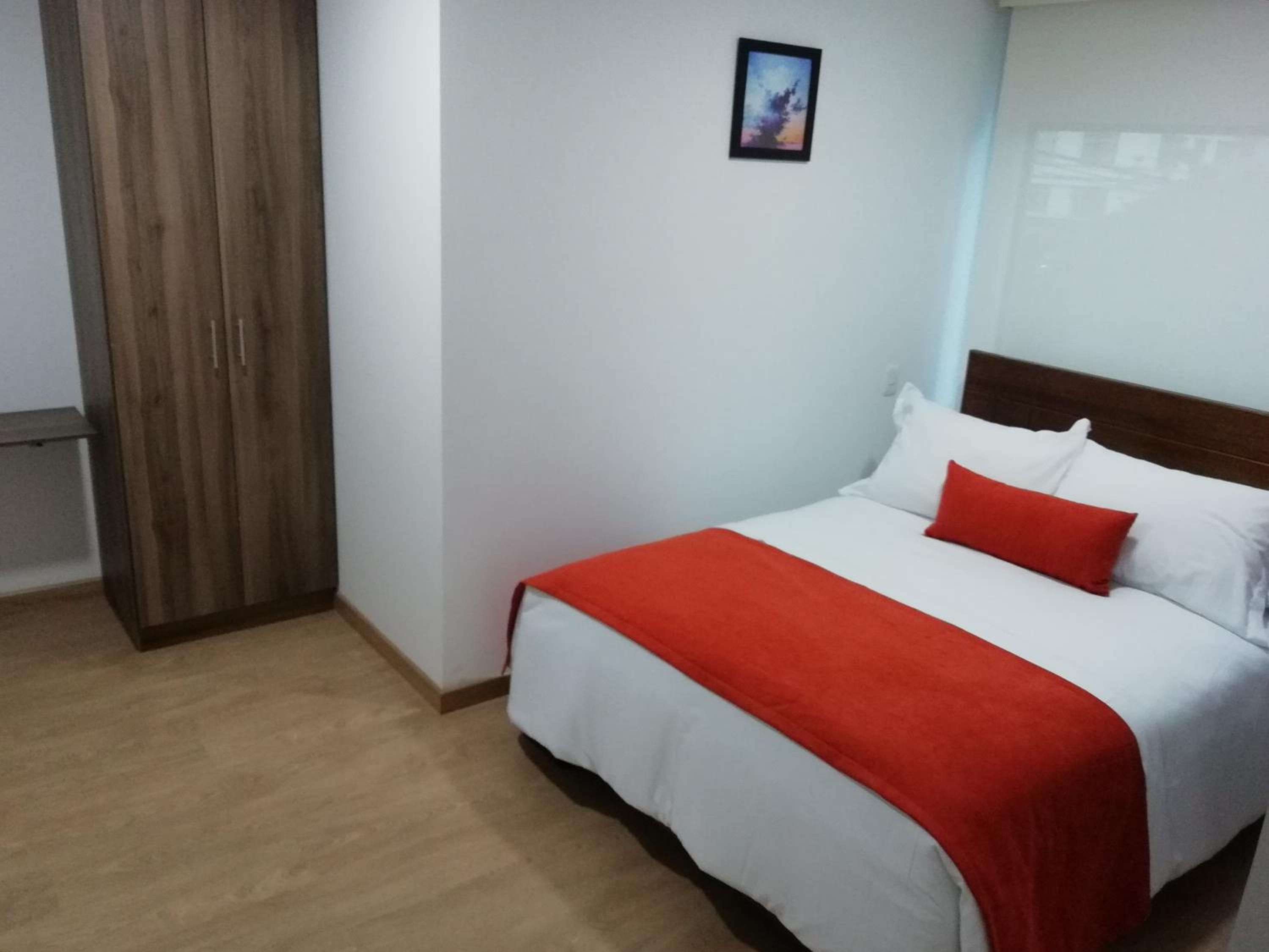 A hotel room with a bed, a wardrobe, and a picture on the wall.