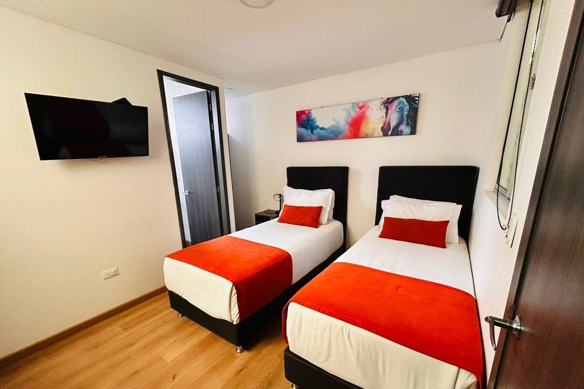Habitació d'hotel amb dos llits, una televisió de pantalla plana, un quadre i un terra de fusta.