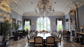 A formal dining room with a long table, ornate chandelier, and classical architecture. - The Inn At Houmas House (Darrow)