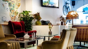 A cozy dining area with a red chair, a table with a vase and glasses, and a large map on the wall. - Best Western Hotel Carlton (Helsinki)