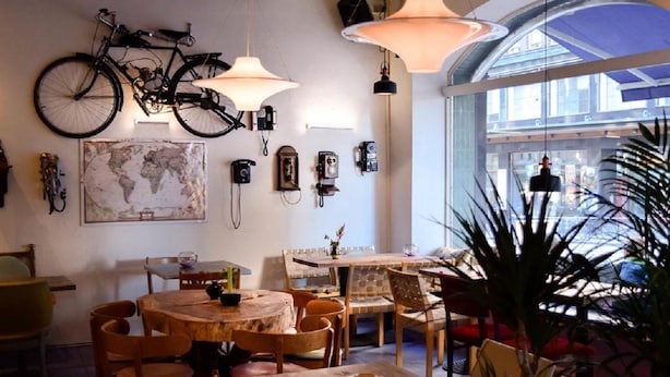 A dining area with a round wooden table, chairs, and a bicycle mounted on the wall. - Best Western Hotel Carlton (Helsinki)