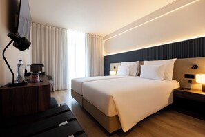 Een moderne hotelkamer met een groot bed, nachtkastjes, een bureau met lamp en een aan de muur bevestigde televisie.