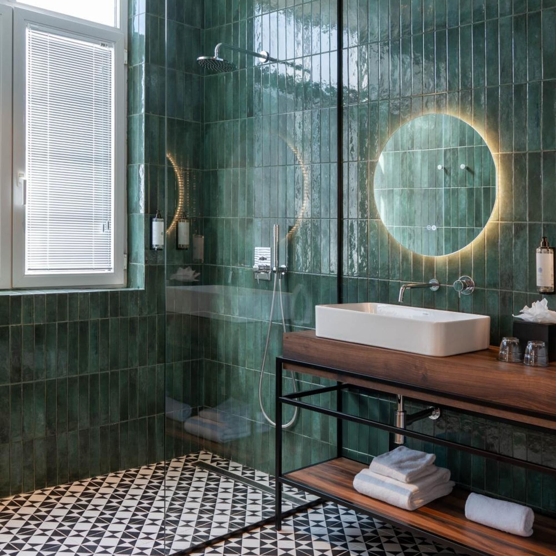 Un baño con un espejo grande, un lavabo, ducha y ventana con persianas.