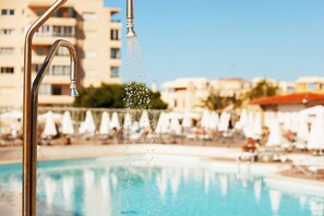 Una piscina al aire libre de temporada, sombrillas