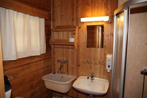 A wooden cabin bathroom with two sinks, a mirror, and a shower. - Vesterland Feriepark Apartments (Sogndal)