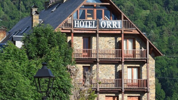 Een hotel met een stenen gevel, meerdere balkons en een bord met de tekst 'HOTEL ORRI'.