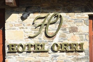 Un mur de pierre sur lequel est apposée une enseigne indiquant « HÔTEL ORRI », avec des lettres grandes et en caractères gras.