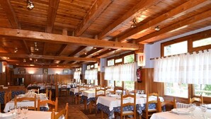 Een restaurant met houten balken, witte tafels en stoelen.