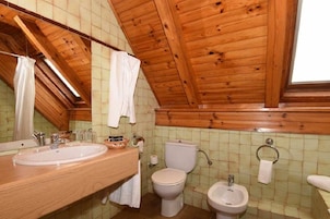 Un baño con paneles de madera, un espejo grande, un lavamanos, un inodoro y un bidé.