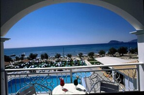A balcony with a view of a beach and a pool. - Astir Palace (Zakynthos)