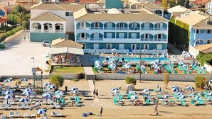 A coastal hotel with multiple balconies, a swimming pool, and numerous beach umbrellas. - Astir Palace (Zakynthos)