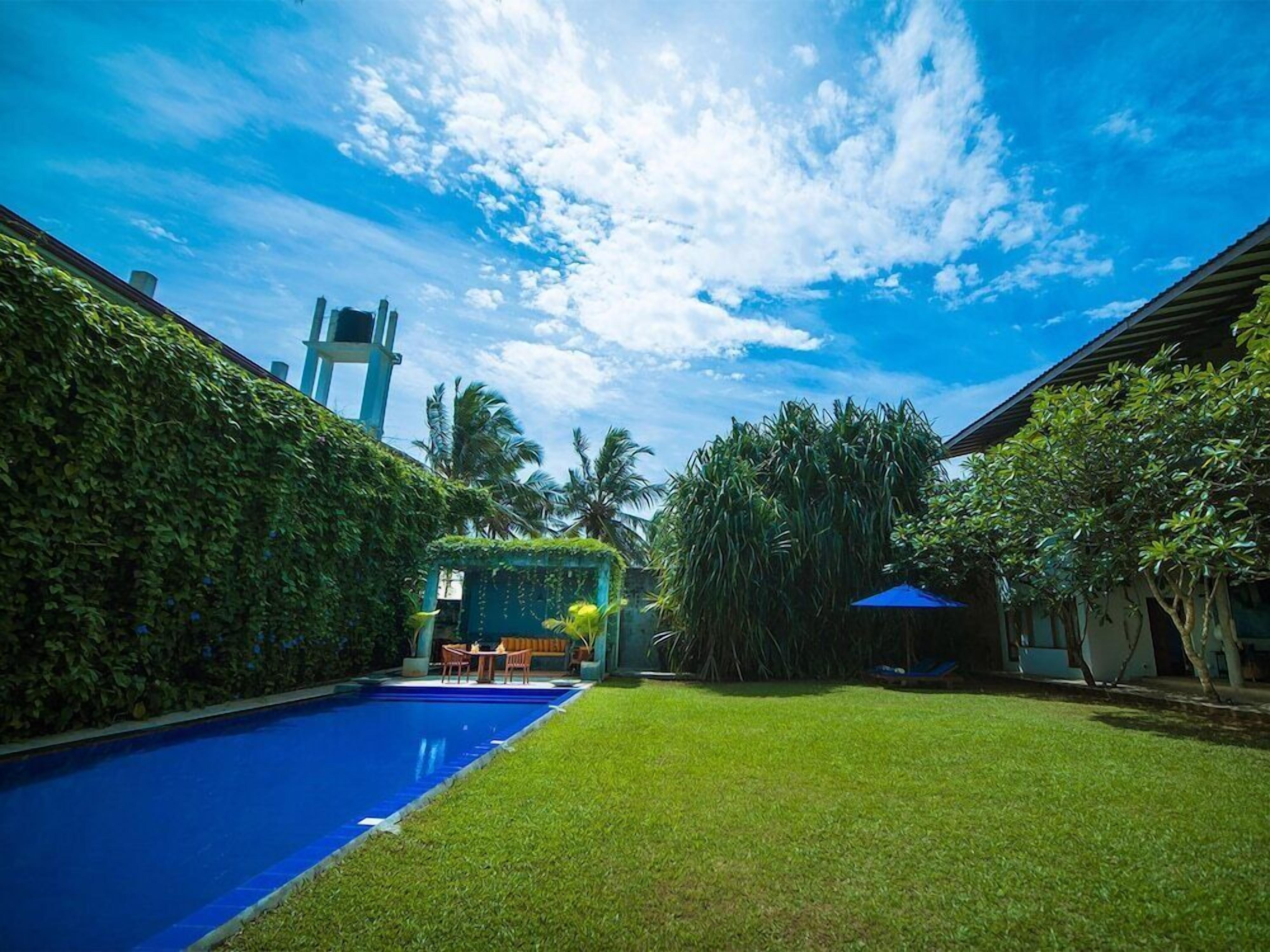 A swimming pool surrounded by lush greenery and a clear blue sky.