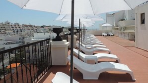 A rooftop terrace with white lounge chairs and umbrellas, offering a view of a coastal town. - Albufeira Beach Hotel (Albufeira)