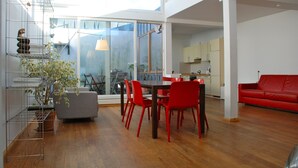 A spacious living area with a dining table, red chairs, a red sofa, and a staircase with a metal railing. - Bright loft in the Kastanienallee (Berlin)