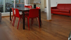 A spacious living area with a dining table and chairs, a red sofa, and a kitchen in the background. - Bright loft in the Kastanienallee (Berlin)